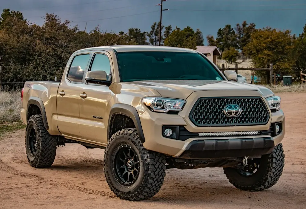 Pick-up 4×4 beige sur une piste en terre