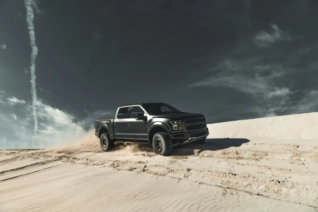 Pick-up 4×4 double cabine noir sur un terrain sablonneux