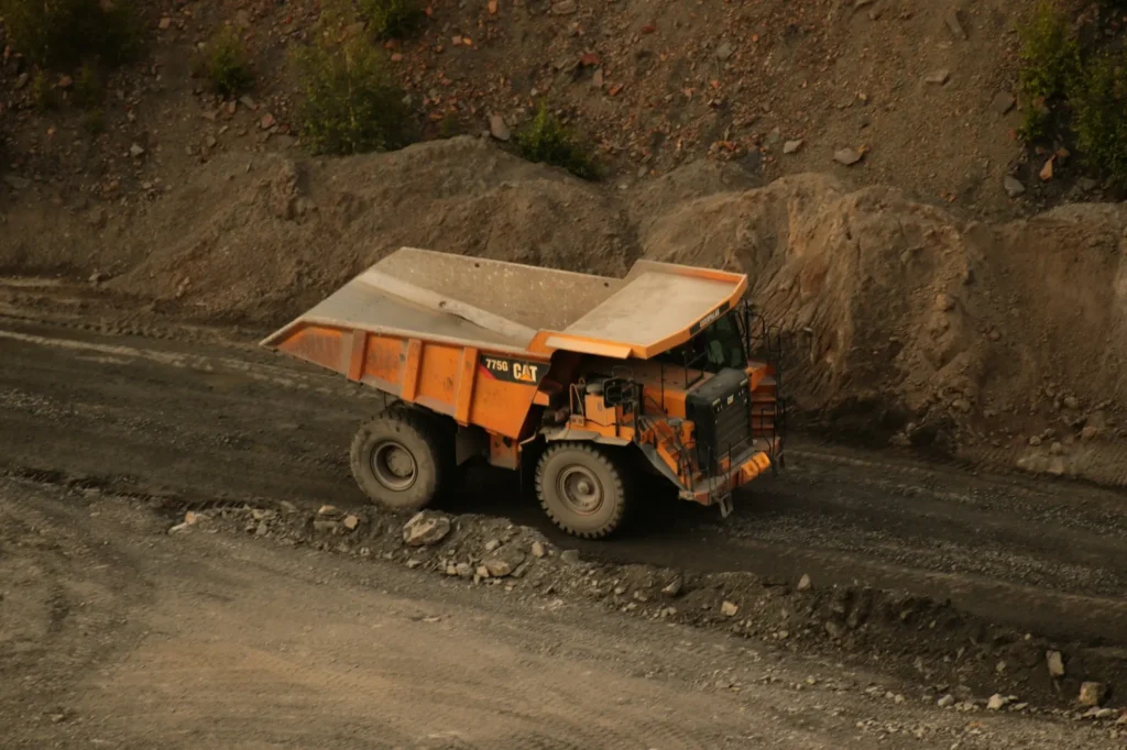 Camion benne orange sur une piste de chantier