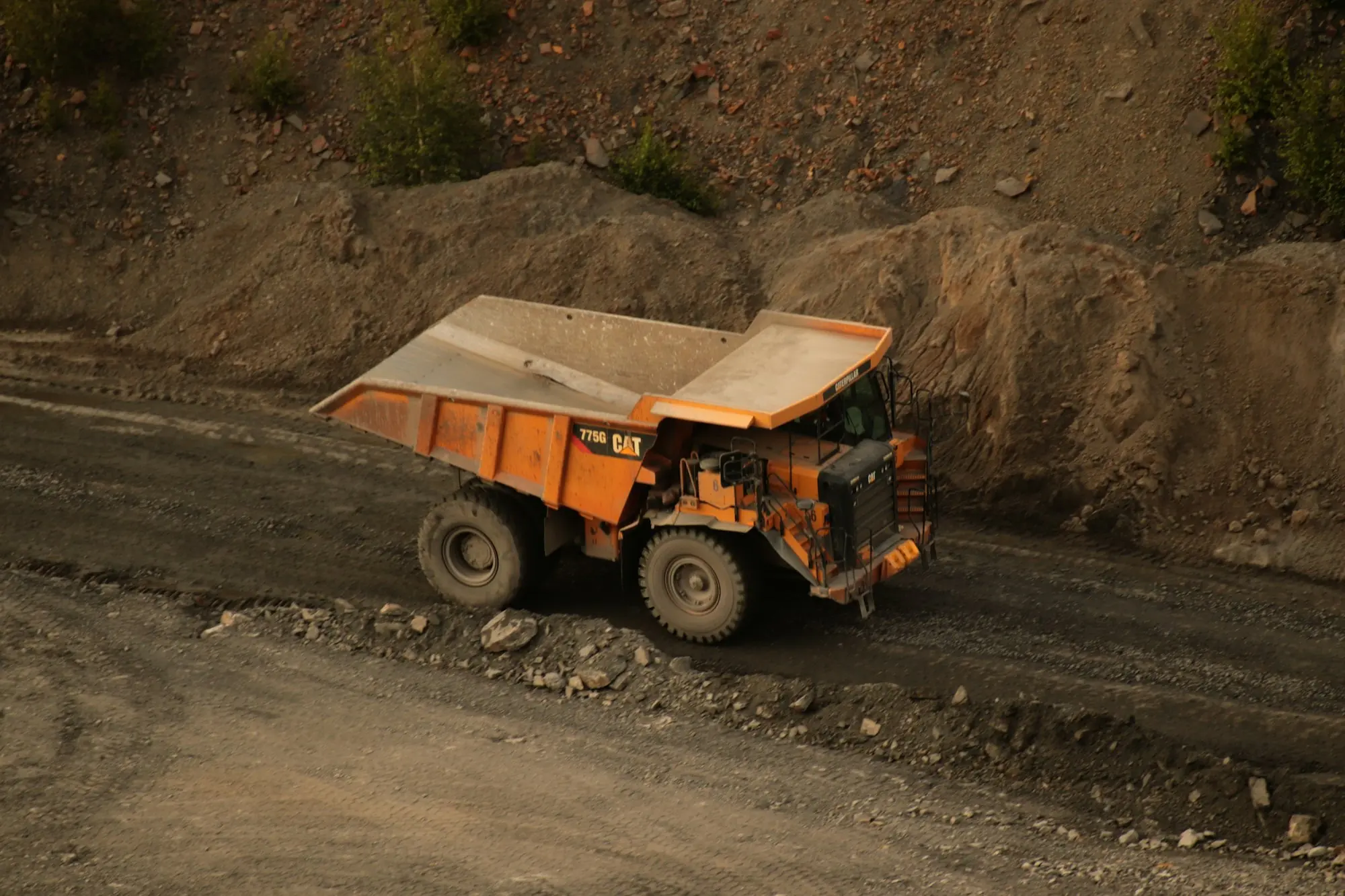 Camion benne orange sur une piste de chantier