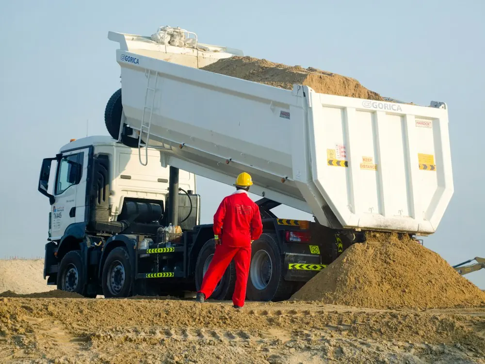 Chef de chantier supervisant le déchargement d’un camion benne